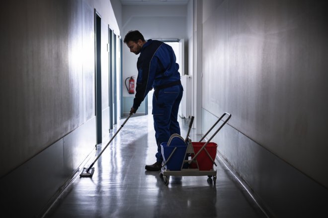 Professional cleaner mopping the corridor of a commercial building